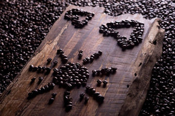 Coffee beans lie in the shape of the sun and in the shape of a heart on a wooden board