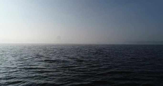 A huge barge on the river Dnipro in the morning fog with a visible silhouette of the buildings and city in the background (shot from the air) in 4K 1