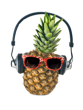 Pineapple closeup with headphones. Music background. Natural healthy fruit. Fashionable sunglasses. Ripe juicy pineapple. Isolated on white.