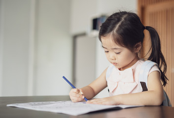 Back to school, Cute little girl painting a picture in home, Girl writing in notebook with pencil at her bedroom. 
