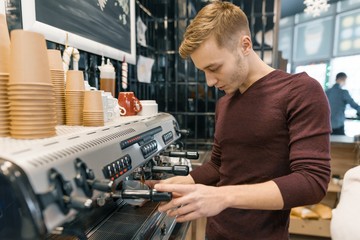 Portrait of young male barista making drinks. Coffee shop business concept