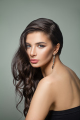 Beautiful dark brown hair woman. Fashion model with long perfect hairstyle, makeup and jewelry earrings