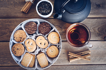 flat lay of Danish butter cookies with a cup of tea and kettle, iron, dry leaves and cinnamon