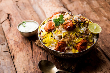 Indian Chicken Tikka Biriyani served in a bowl with yogurt. selective focus