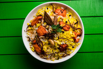Indian Chicken Tikka Biriyani served in a bowl with yogurt. selective focus