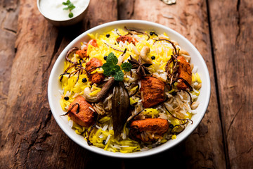 Indian Chicken Tikka Biriyani served in a bowl with yogurt. selective focus