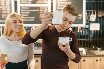 Barista man and woman making coffee, couple of young people working in coffee shop