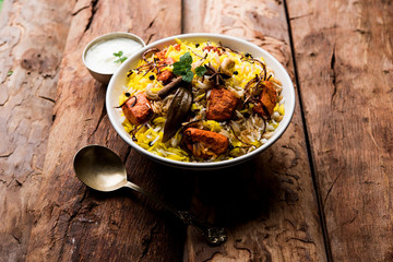 Indian Chicken Tikka Biriyani served in a bowl with yogurt. selective focus