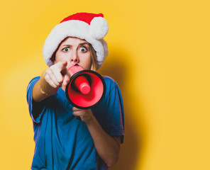 Young style girl in purple clothes and Christmas hat with pink megaphone on yellow background. Symbolizes female resistance. Clothes in 1980s style