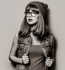 Portrait of young style hipster girl in hat and glasses . Image in black and white color style