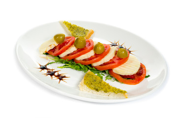 Caprese salad with mozzarella, tomato, basil and balsamic vinegar arranged on white plate