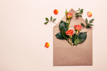 Spring concept. Paper envelope with mini coral roses on a pink background