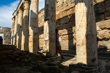 Fototapeta premium Beautiful Young woman with dark hair posing in Old ancient ruins of roman City Hierapolis in Pamukkale, Turkey 