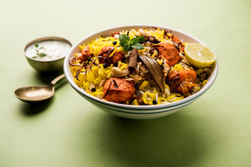 Indian Chicken Tikka Biriyani served in a bowl with yogurt. selective focus
