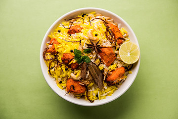 Indian Chicken Tikka Biriyani served in a bowl with yogurt. selective focus