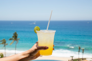 A woman holds a margarita drink at the beach