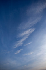 Blue sky with light cloud pattern at sunset vertical composition