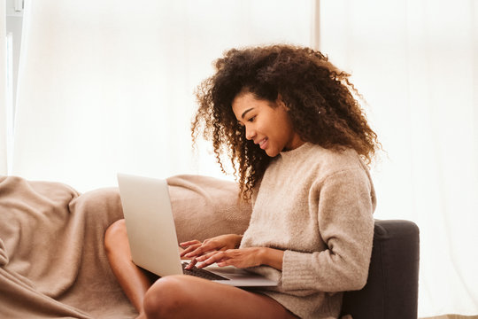 Black female using laptop on sofa