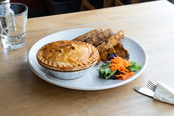 Minced meat pie made with beef and served with large potato wedges. Australian and English meat pie served with fries. 