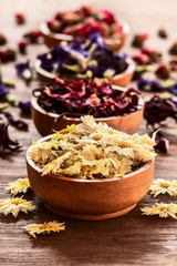 Assortment of dry tea in wooden bowls on old rustic background.