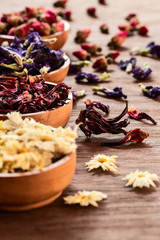 Assortment of dry tea in wooden bowls on old rustic background.