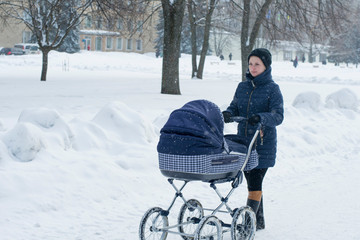 Mother walks with a stroller on a snowy winter day