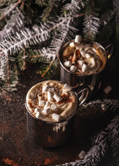 Hot drinks, chocolate with whipped cream and marshmallow in metal mugs, cozy christmas composition.