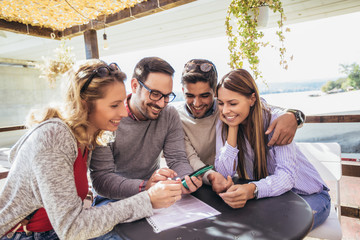 Group of four friends having fun a coffee together. Two women and two men at cafe talking laughing...