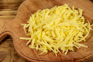 Grated cheese on cutting board on wooden table