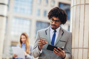 African man outdoor holding gadget and payment card