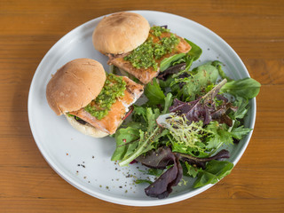 Salmon sliders with a side salad. Fresh-grilled salmon served as sandwiches with a homemade sauce. Fish for lunch.