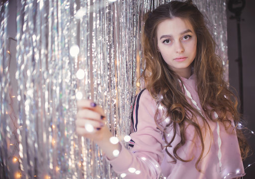 gentle and beautiful young girl on the background of garlands and tinsel