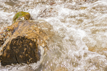 big stone streamlined by water on a small river in a small cascade