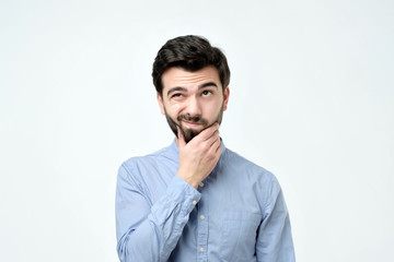 Pensive spanish man in blue shirt against a white background