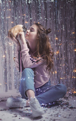 Obraz premium gentle and beautiful young girl on the background of garlands and tinsel with Guinea pig