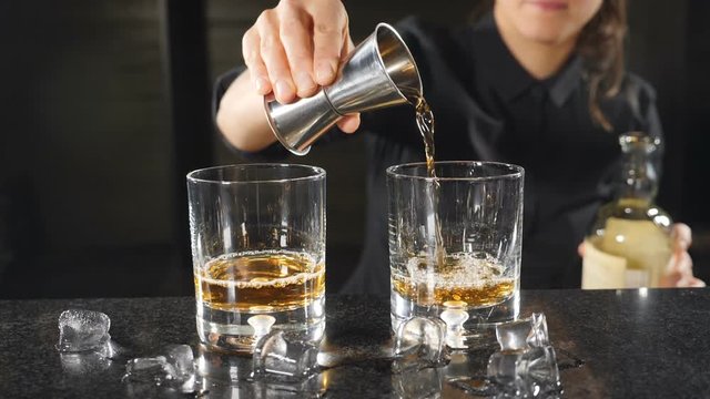 Premium Photo  Pouring whisky from a jigger into a rocks glass with a big  ice cube