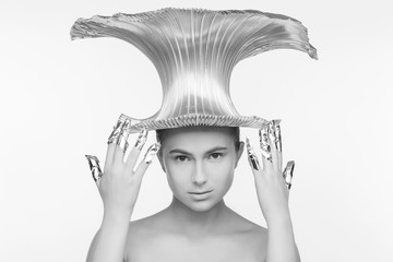 Beautiful woman in a futuristic style, with an iron hat on her head and with fingers that are wrapped in foil