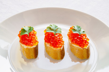 baguette slices with butter and keta caviar decorated with parsley 