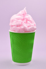 Bright pink candy cotton in plastick cup on lilac background.