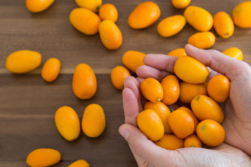 many fresh orange  kumquat a tropical fruit for sale at greengrocer store. Kumkuat and wicker bag from Turkey.