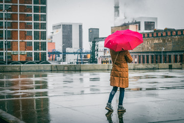 Woman with red umbrella standing in city during snowing © encierro