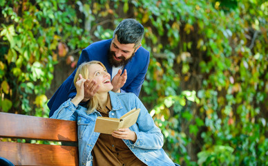 Fototapeta premium Girl sit bench read book while wait boyfriend. Wait him for date. Dating in park. Romantic relations concept. Park best place for romantic date. Couple in love romantic date nature park background