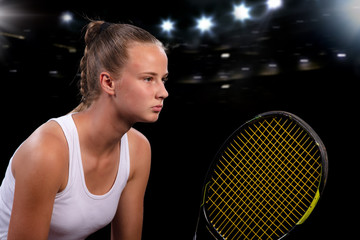 Beautiful girl tennis player with a racket on dark background with lights