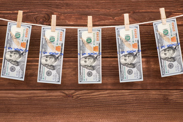 US dollar banknotes hanging on rope on wooden background for money laundering concept