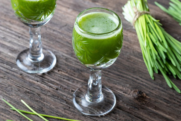A glass of barley grass juice, with fresh barley grass in the background