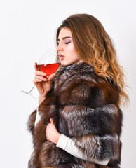 Reasons drink red wine in wintertime. Woman drink wine. Girl fashion makeup wear fur coat hold...