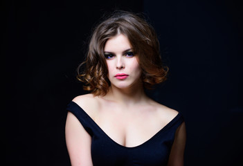 Fototapeta premium Woman with curly hairstyle and makeup on black background. Makeup idea for elegant outfit. Attractive elegant lady with smoky eyes makeup and pink lipstick. Professional makeup. Beauty salon concept