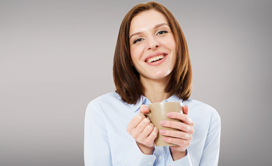 Laughing beautiful brunette woman with cup of coffee on grey background. Copy space
