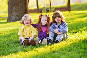 Fototapeta premium group of happy little children smiling sitting in park on grass under a tree. June 1, Children's Day, friendship, childhood, vacation.