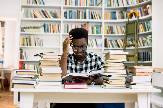 Worried African Student Looking At Books On Desk In Library